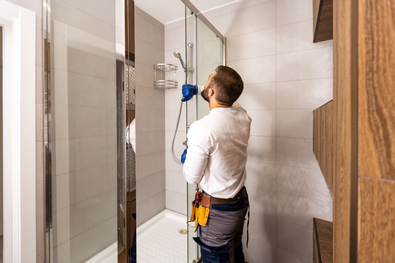 a tradie fits a glass door onto a shower