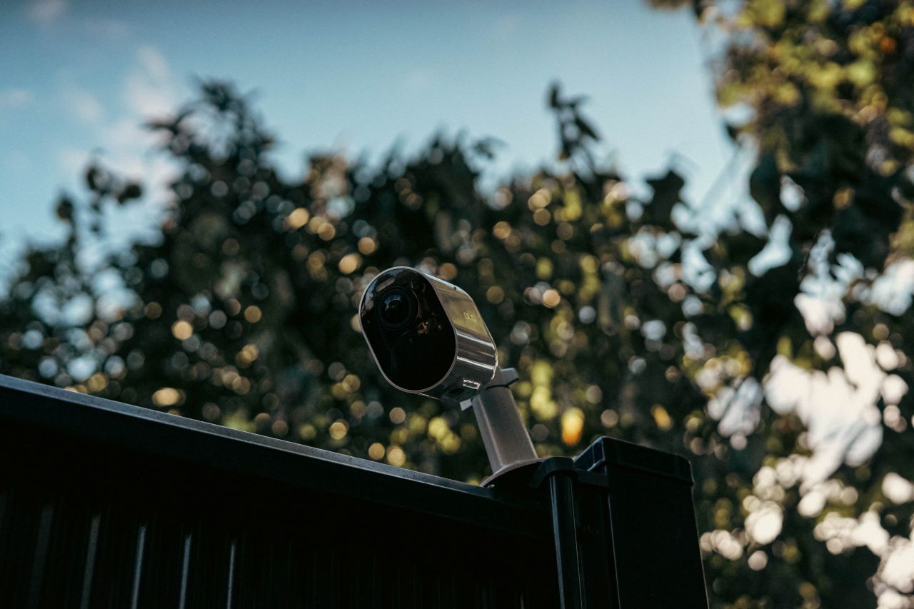 a security camera on top of a fence in the evening.
